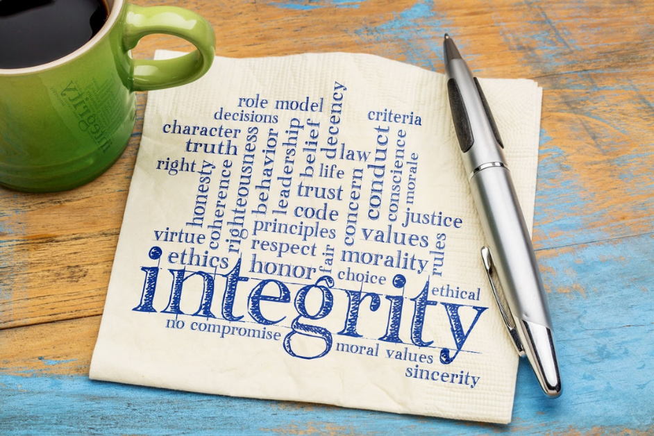 A word cloud centered on the word Integrity is printed in blue ink on a white paper napkin. Related terms in the word cloud include Honesty, Virtue, and Ethics.